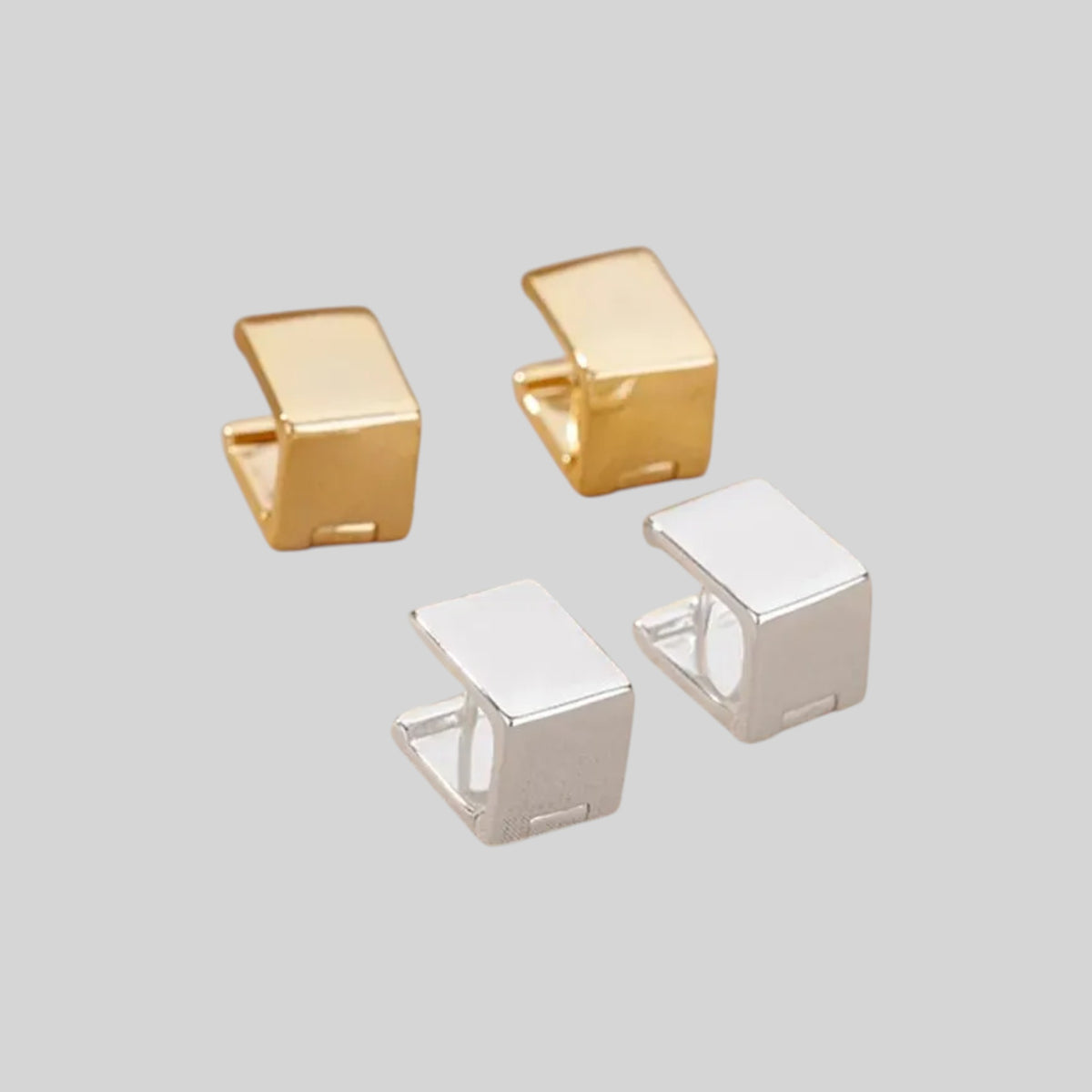 Four small cube-shaped jewelry findings or connector pieces shown on a plain light gray background, with two in gold-tone finish and two in silver-tone finish.