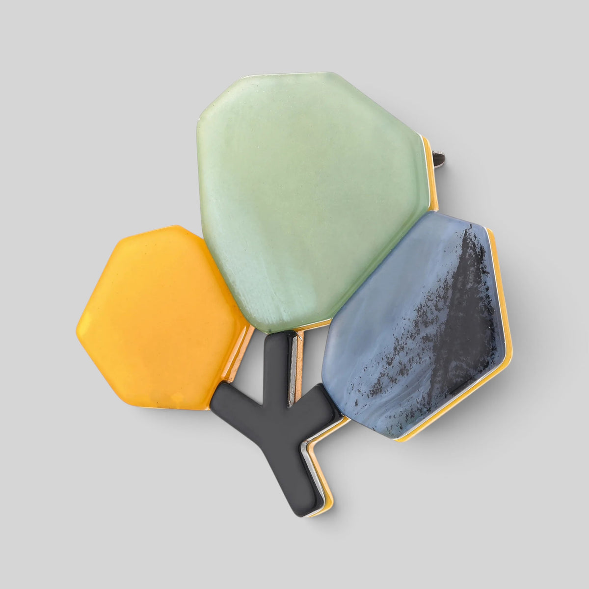 A cluster of three hexagonal decorative pieces with black Y-shaped stems, featuring a light green piece, a mustard yellow piece, and a blue-and-black marbled piece with gold-toned edges, set against a solid gray background.