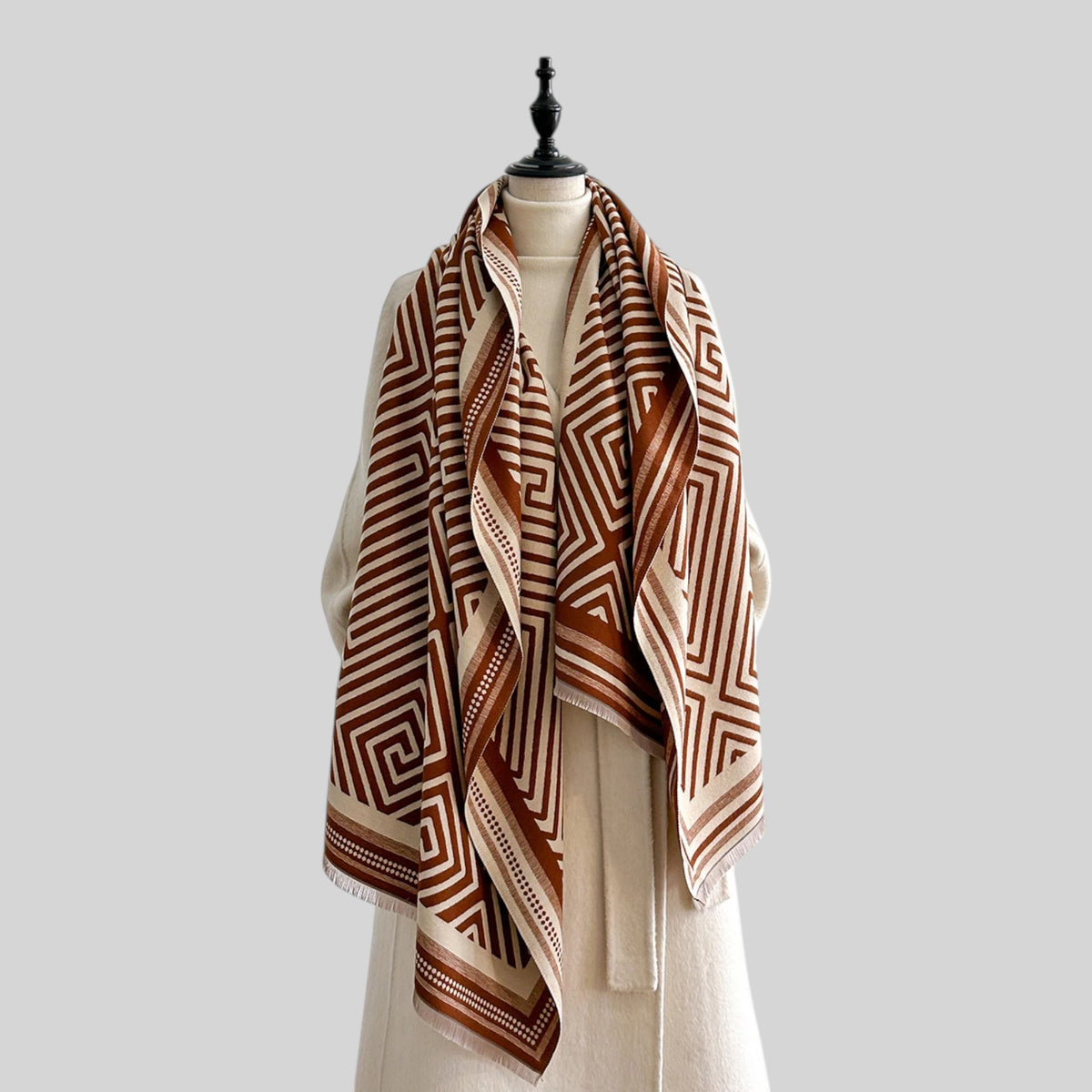 A blue and white geometric patterned silk scarf tied around a white mannequin dress form with a wooden neck cap, set against a solid light gray background.