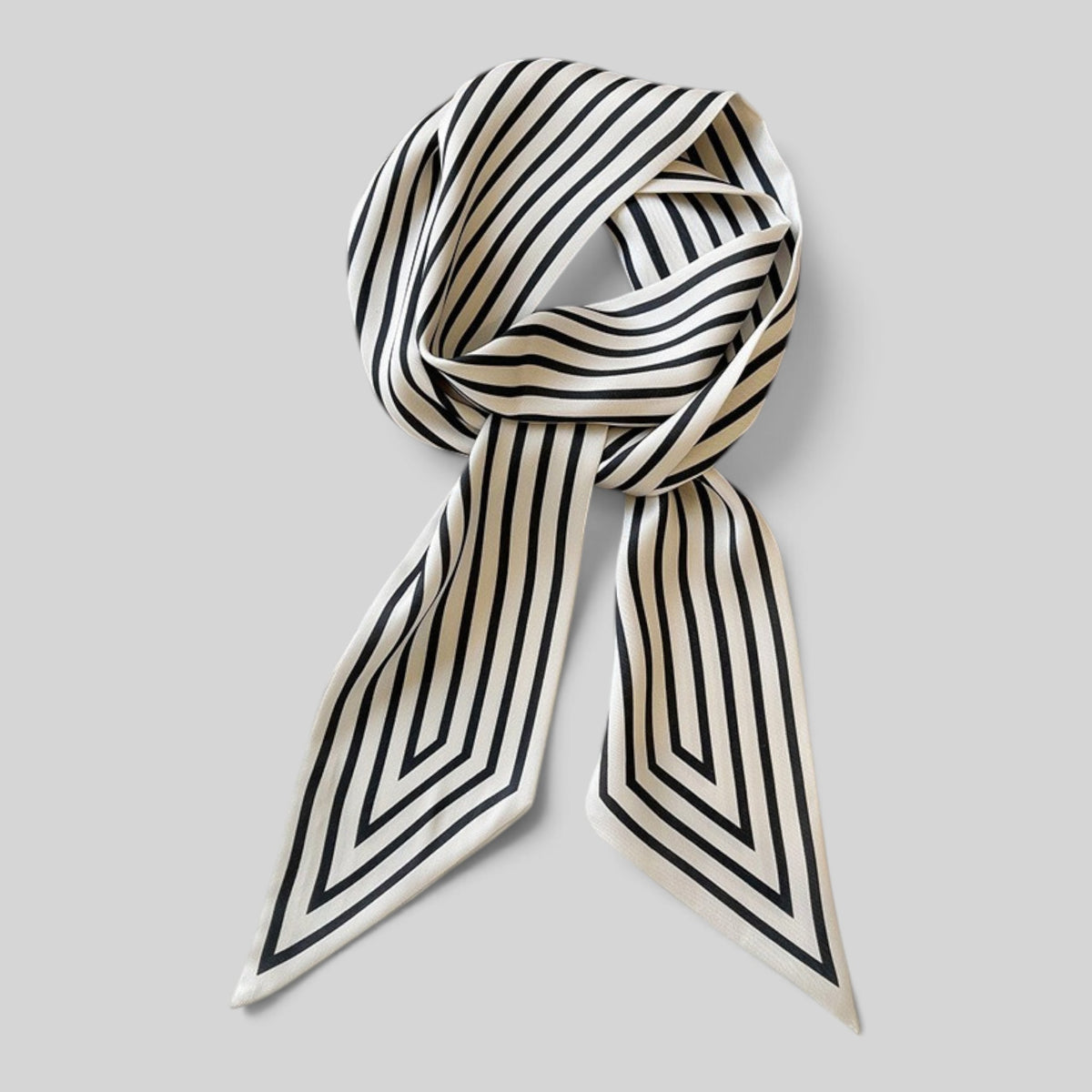 A silk scarf with a black and cream geometric striped pattern, styled in a loose knot against a solid light gray background.