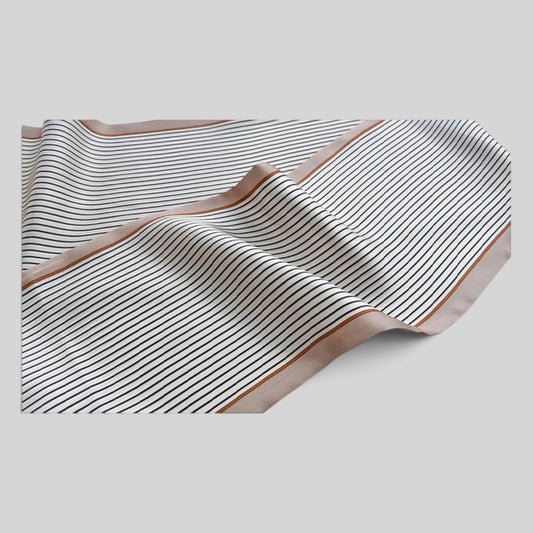 A square scarf with thin black stripes on a warm beige background and a solid tan border, draped elegantly on a light gray background.