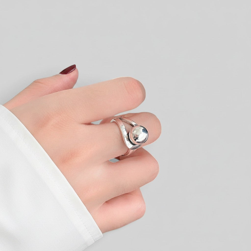 A silver ring with a polished oval stone worn on a person's finger, shown against a plain light gray background.