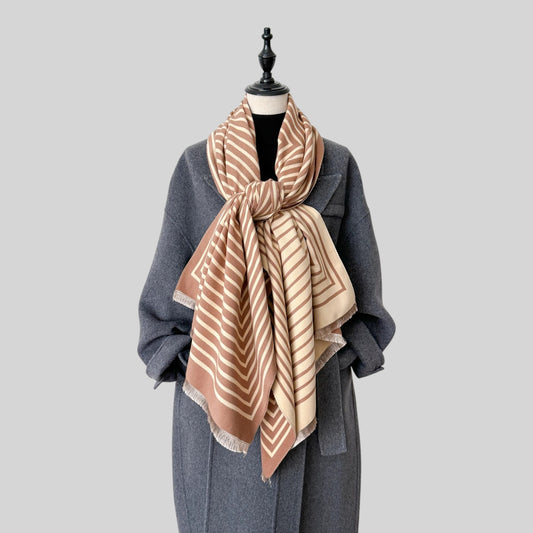 A mannequin with a grey long coat and a long rust orange and beige scarf with a knot.