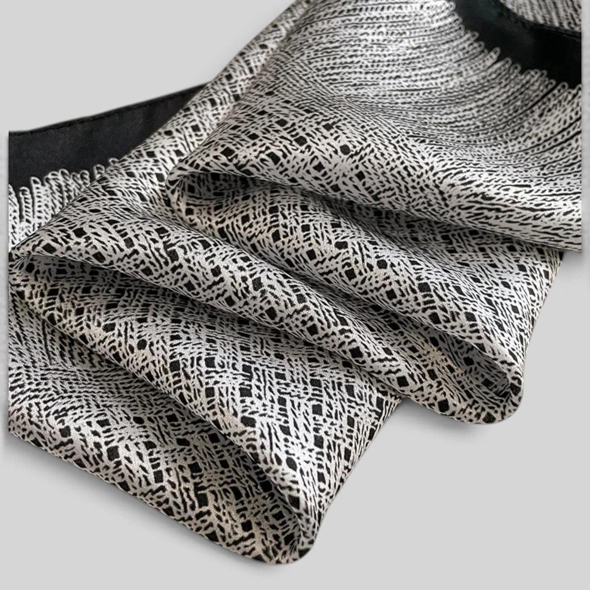 Close-up of fine rhythmic geometric print on fluid black and grey mulberry silk