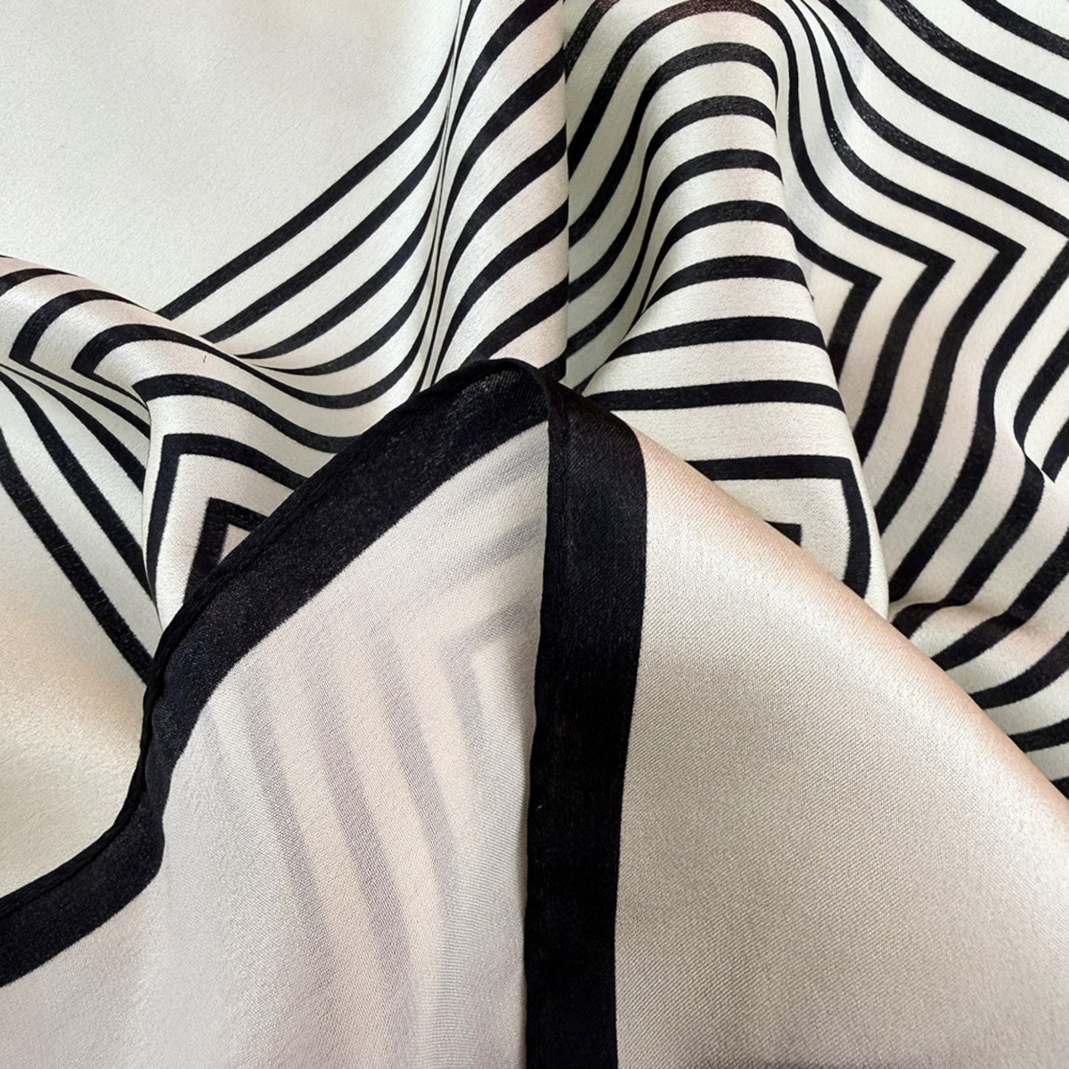Close-up of rolled edges and high-contrast geometric pattern on pure silk crepe satin